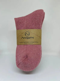 A pair of pink Moggans Cashmere Bed Socks, made in Scotland, wrapped with a brown paper label featuring the brand's logo and text: "Luxury Cashmere Lounge Socks Made in Scotland.