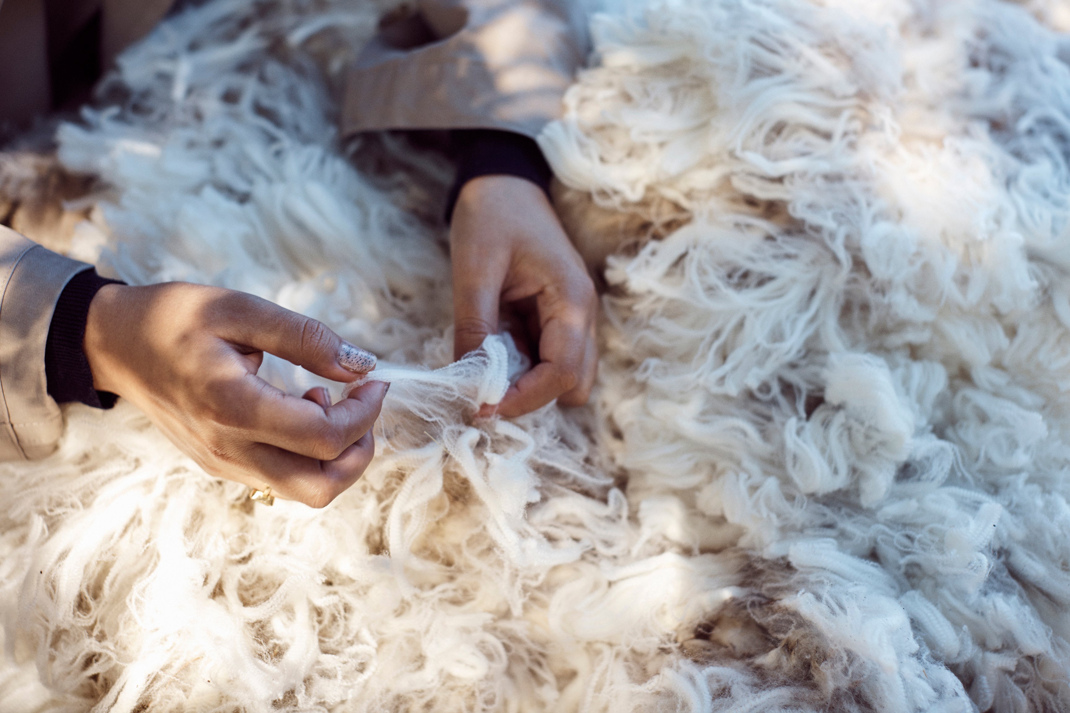Close-up of hands working with white yarn on a textured surface