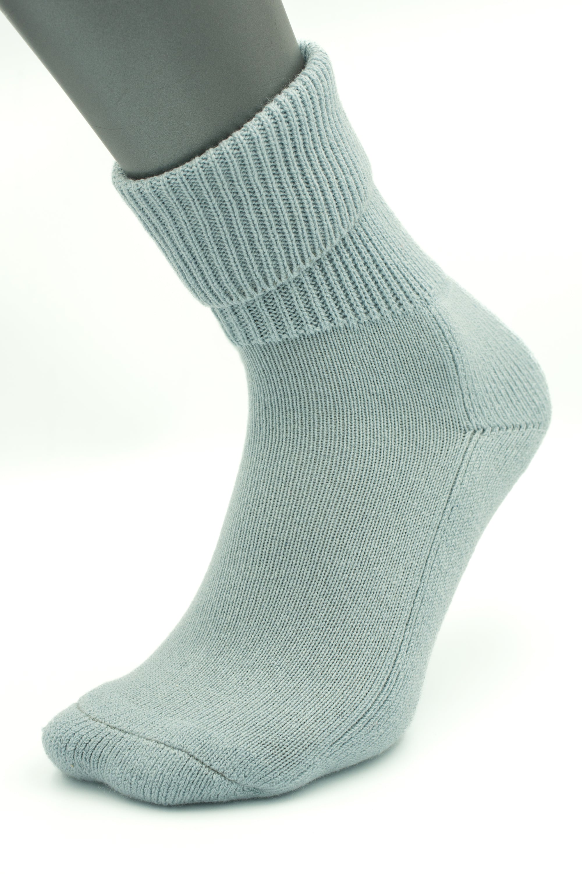 The Moggans NEW for 2025: Cashmere Luxury Bed Socks, made in Scotland, are shown in light gray on a mannequin foot with a folded cuff and seamless design against a plain white background.