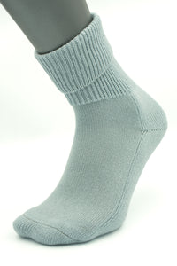 The Moggans NEW for 2025: Cashmere Luxury Bed Socks, made in Scotland, are shown in light gray on a mannequin foot with a folded cuff and seamless design against a plain white background.