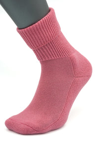 A mannequin foot displays a single, thick pink Moggans Cashmere Luxury Bed Sock with a folded cuff, set against a white background. NEW for 2025 and made in Scotland.