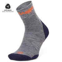 A single Lightweight Merino Ankle Sock by Moggans in gray and navy, with orange branding, is displayed upright. The Woolmark logo and Wool Rich Blend in the corner highlight its moisture-wicking running performance.